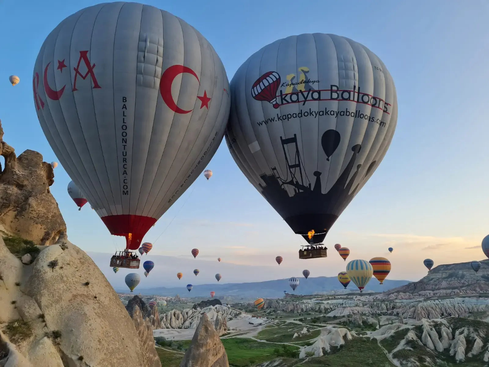 Hot air balloons floating beside Cappadocia’s rock formations